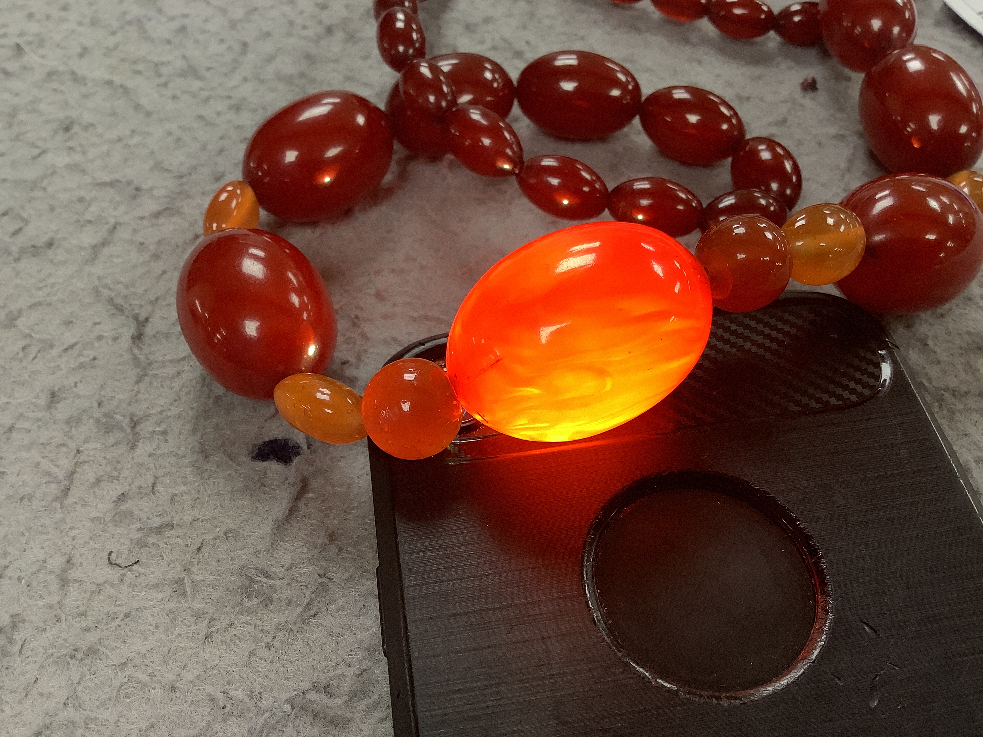 A single strand graduated simulated cherry amber bead necklace, with four simulated orange amber beads, 66cm, gross weight 84 grams.